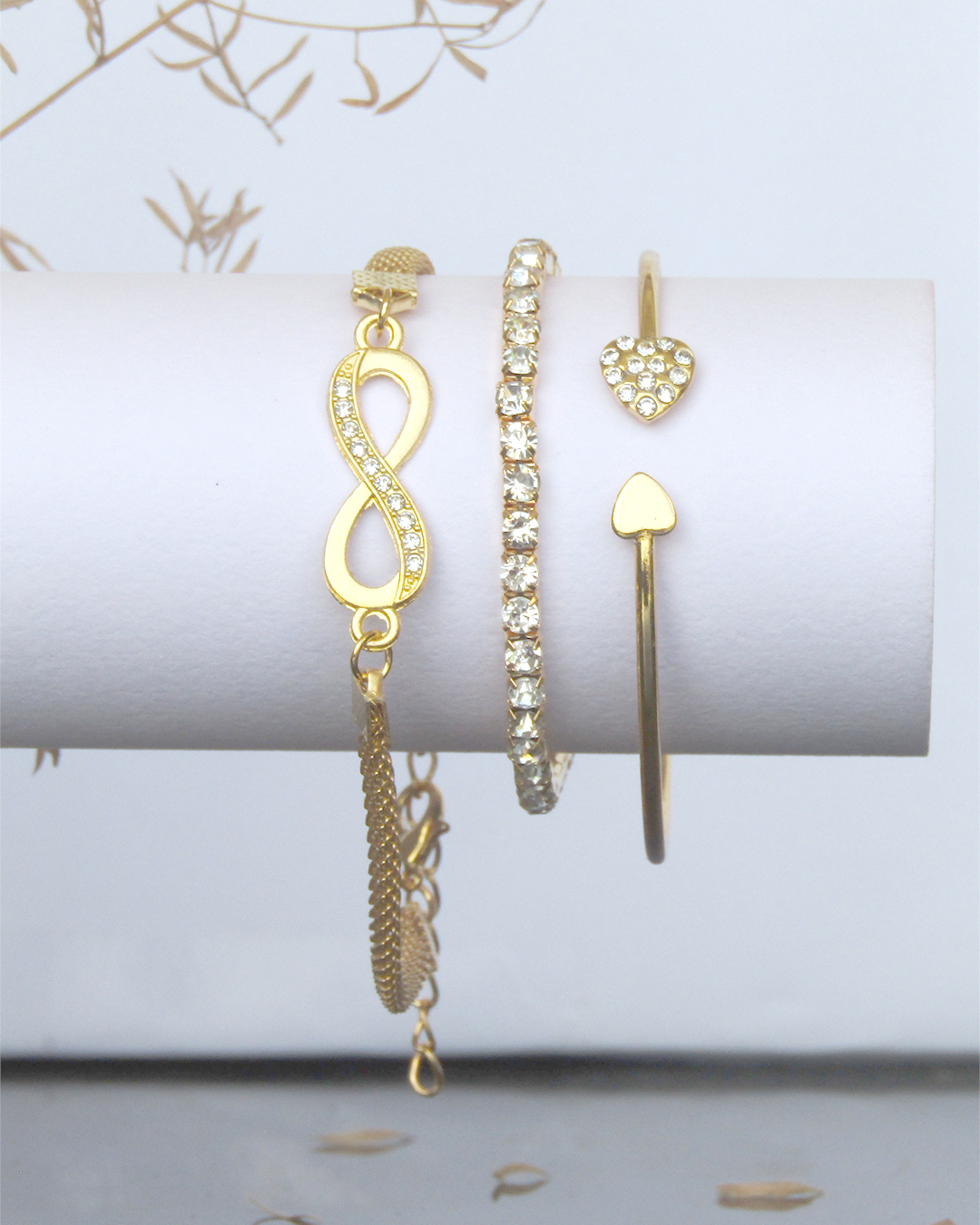 Set of gold Plated jewelry including earrings and bracelets on a white surface with a light background.